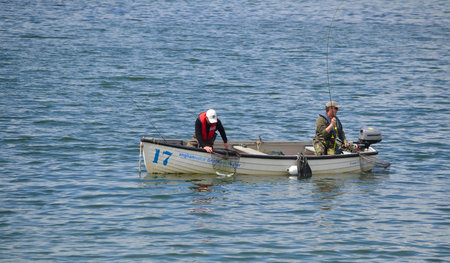 Two fisherman fishing with rods in boat.