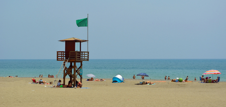 Torremolinos Beach with holiday makers and watch tower with green flag  overlooking Mediterranean Sea,のeditorial素材