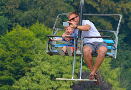 CORTON, SUFFOLK, ENGLAND - AUGUST 23, 2017: Man taking selfie with little boy while riding on a...