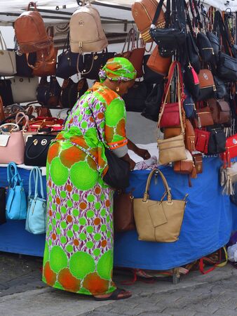 TEGUISE, LANZAROTE, SPAIN - March 18, 2018: Market stall trader in colorful  outfit selling handbags.のeditorial素材