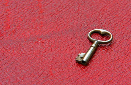 Tiny Antique Key on Red Leather surface.の写真素材