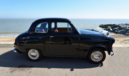 Classic Black 2 Door  Baby Austin A30 Parked on seafront promenade beach and sea in background.のeditorial素材