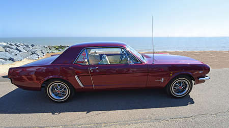 Classic Purple Ford Mustang parked on seafront beach and sea in background.のeditorial素材