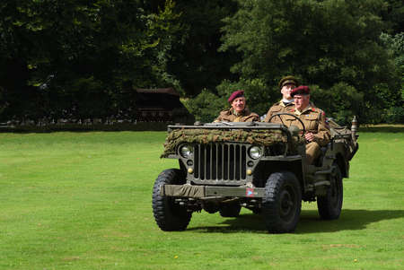 World War 2 Jeep with men dressed as World War 2 British soldiers in red berets.のeditorial素材