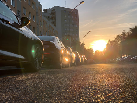 Cars parked in a row on the road in the city at sunset