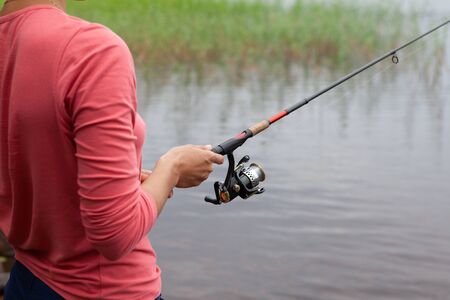 Fishing rod with a fishing reel in a womans handの写真素材