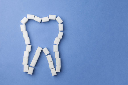 white tooth made of sugar on a blue background. The concept of oral health.