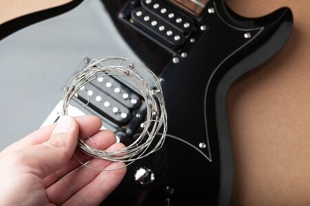 old strings in hand against the background of the body of a guitar without strings.の写真素材