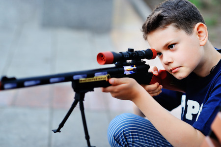 A young boy looks in the sight of a toy rifleの写真素材