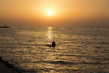this is the best shot of my day. Perfect sunset, orange, red sky and excellent clouds. there are some rocks which stand against the waves. The sun is setting on the sea. the water is like bloodの写真素材