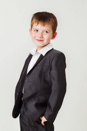 Little boy in a business suit holding his hands in his trouser pocketsの写真素材