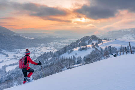 nice active senior woman snowshoeing in the Allgaeu Alps near Oberstaufen with view into the Bregenzerwald, Vorarlberg, Austriaの写真素材