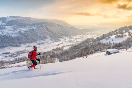 nice active senior woman snowshoeing in the Allgaeu Alps near Oberstaufen with view into the Bregenzerwald, Vorarlberg, Austriaの写真素材