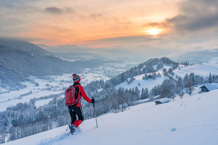 nice active senior woman snowshoeing in the Allgaeu Alps near Oberstaufen with view into the Bregenzerwald, Vorarlberg, Austriaの写真素材