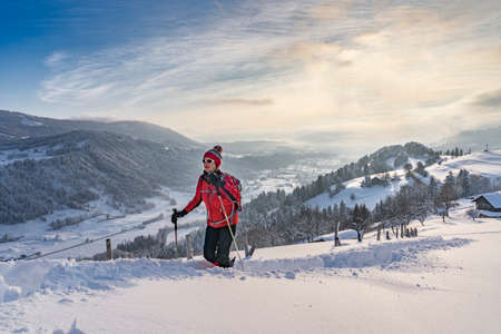 nice active senior woman snowshoeing in the Allgaeu Alps near Oberstaufen with view into the Bregenzerwald, Vorarlberg, Austriaの写真素材