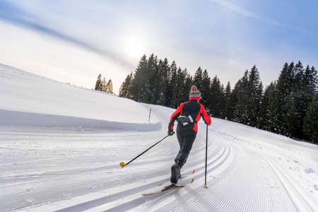 beautiful active senior woman cross-country skiing in fresh fallen powder snow in the Allgau alps near Immenstadt, Bavaria, Germanyの写真素材