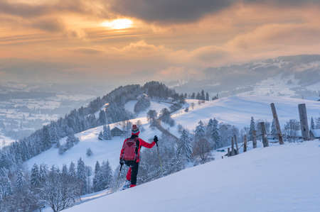 nice active senior woman snowshoeing in the Allgaeu Alps near Oberstaufen with view into the Bregenzerwald, Vorarlberg, Austriaの写真素材
