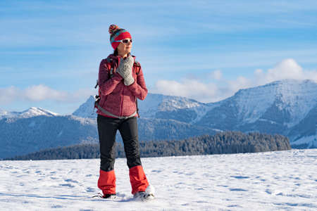 nice active senior woman snowshoeing in the Allgaeu Alps near Oberstaufen with view into the Bregenzerwald, Vorarlberg, Austriaの写真素材