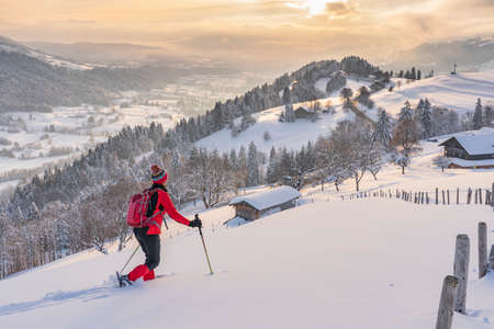 nice active senior woman snowshoeing in the Allgaeu Alps near Oberstaufen with view into the Bregenzerwald, Vorarlberg, Austriaの写真素材