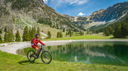 pretty senior woman riding her electric mountain bike on the Wallraff Trail in the Nebelhorn area above Oberstdorf, Allgau Alps, Bavaria,の写真素材