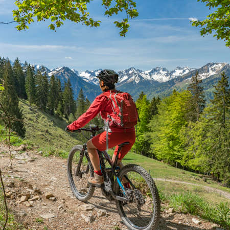 pretty senior woman riding her electric mountain bike on the Wallraff Trail in the Nebelhorn area above Oberstdorf, Allgau Alps, Bavaria,の写真素材
