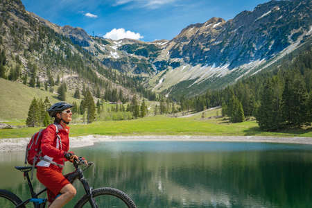 pretty senior woman riding her electric mountain bike on the Wallraff Trail in the Nebelhorn area above Oberstdorf, Allgau Alps, Bavaria,の写真素材