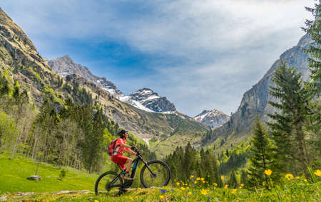 pretty senior woman riding her electric mountain bike the Oy Tal Valley near Oberstdorf, Allgau Alps, Bavaria, Germanyの写真素材