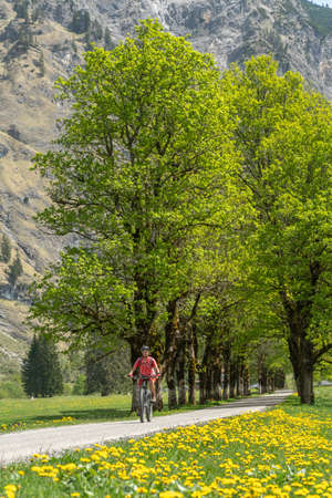 pretty senior woman riding her electric mountain bike the Oy Tal Valley near Oberstdorf, Allgau Alps, Bavaria, Germanyの写真素材