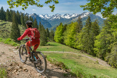 pretty senior woman riding her electric mountain bike on the Wallraff Trail in the Nebelhorn area above Oberstdorf, Allgau Alps, Bavaria,の写真素材