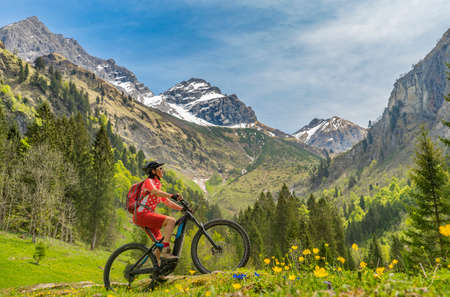 pretty senior woman riding her electric mountain bike the Oy Tal Valley near Oberstdorf, Allgau Alps, Bavaria, Germanyの写真素材