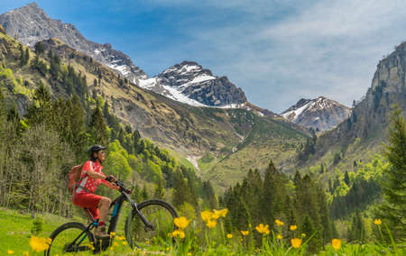pretty senior woman riding her electric mountain bike the Oy Tal Valley near Oberstdorf, Allgau Alps, Bavaria, Germanyの写真素材