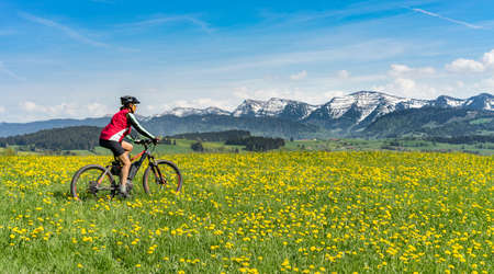 senior woman mountainbiking on a e-mountainbike in early spring, in the Allgaeu Area, a part of the bavarian alps, Germanyの写真素材