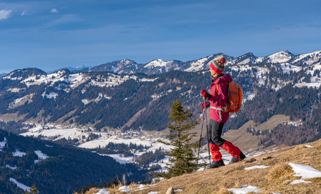 nice and active senior woman winter hiking in the Allgau alps with view to the Nagelfluh chain near Balderschwang, Bavaria, Germanyの写真素材
