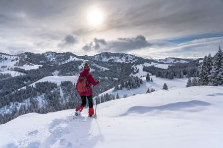 nice and active senior woman snowshoeing in deep powder snow in the Allgau alps, Bavaria, Germanyの写真素材