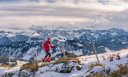 nice and active senior woman snow hiking in deep powder snow in the Allgau alps in the Grasgehren Area above Balderschwang, Bavaria, Germanyの写真素材