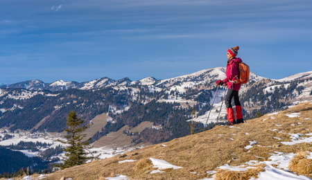 nice and active senior woman winter hiking in the Allgau alps with view to the Nagelfluh chain near Balderschwang, Bavaria, Germanyの写真素材