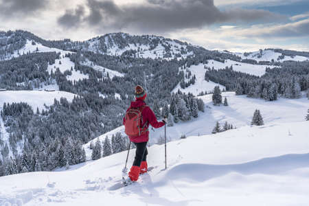 nice and active senior woman snowshoeing in deep powder snow in the Allgau alps, Bavaria, Germanyの写真素材