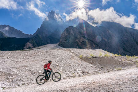 pretty senior woman riding her electric mountain bike in the Innerfeld Valley in the Sexten Dolomites near village of Innichen, Tre cime National park, South Tirol, Italyの写真素材