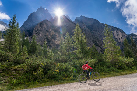 pretty senior woman riding her electric mountain bike in the Innerfeld Valley in the Sexten Dolomites near village of Innichen, Tre cime National park, South Tirol, Italyの写真素材