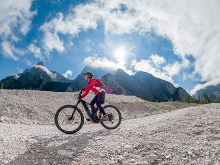 pretty senior woman riding her electric mountain bike in the Innerfeld Valley in the Sexten Dolomites near village of Innichen, Tre cime National park, South Tirol, Italyの写真素材