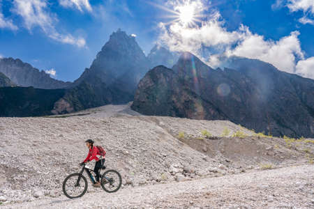 pretty senior woman riding her electric mountain bike in the Innerfeld Valley in the Sexten Dolomites near village of Innichen, Tre cime National park, South Tirol, Italyの写真素材