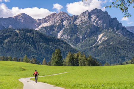 pretty senior woman riding her electric mountainbike in the Prags Dolomites, Tre cime National park, South Tirol, Italyの写真素材