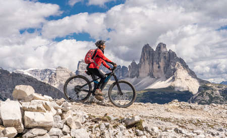 nice senior woman, riding her electric mountain bike below the famous Three peak of Lavaredo in the Sexten Dolomites in South tyrol, Italyの写真素材