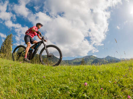 active senior woman riding her electric mountain bike in the Allgau Alps near city of Immenstadt, AlgÃ¤u, Bavaria, Germanyの写真素材