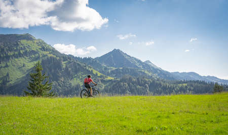 active senior woman riding her electric mountain bike in the Allgau Alps near city of Immenstadt, AlgÃ¤u, Bavaria, Germanyの写真素材