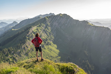 pretty senior woman hiking in the early evening in warm dawn light on the ridge of the Nagelfluh chain in the Allgau Alps near Immenstadt, Bavaria, Germanyの写真素材