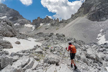 senior woman hiking in the wild terrain below the Drosa Tor in the mountains of Montafon valley, Vorarlberg, Austriaの写真素材