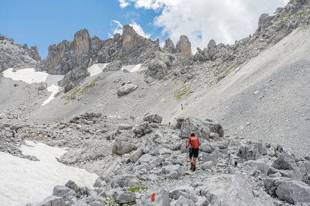 senior woman hiking in the wild terrain below the Drosa Tor in the mountains of Montafon valley, Vorarlberg, Austriaの写真素材