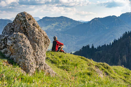 pretty senior woman hiking in warm dawn sunlight and enjoying the spectacular view over the Allgau alps near Oberstdorf, Bavaria, Germanyの写真素材
