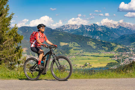 pretty senior woman riding her electric mountain bike on the mountains above the Iller valley between Sonthofen and Oberstdorf, Allgau Alps, Bavaria Germanyの写真素材
